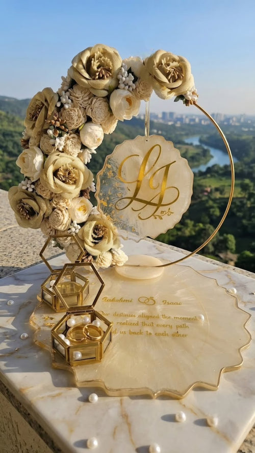Personalized floral wedding ring holder with gold hoop stand, marble base, custom monogram tag, and dual glass ring boxes with pearl accents